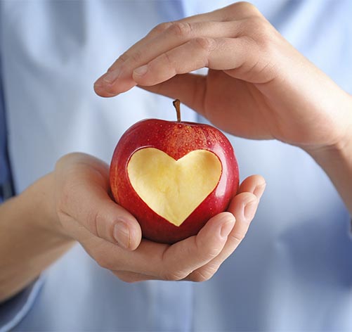 Duas mãos seguram uma maçã em plano próximo.